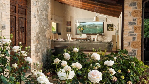 A rustic interior with a stone wall, wooden door, and a cozy seating area with a sofa and table.