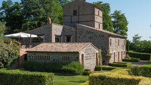 A stone building with a bell tower, surrounded by well-maintained hedges and a clear sky.