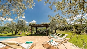 A poolside area with lounge chairs and a pergola.