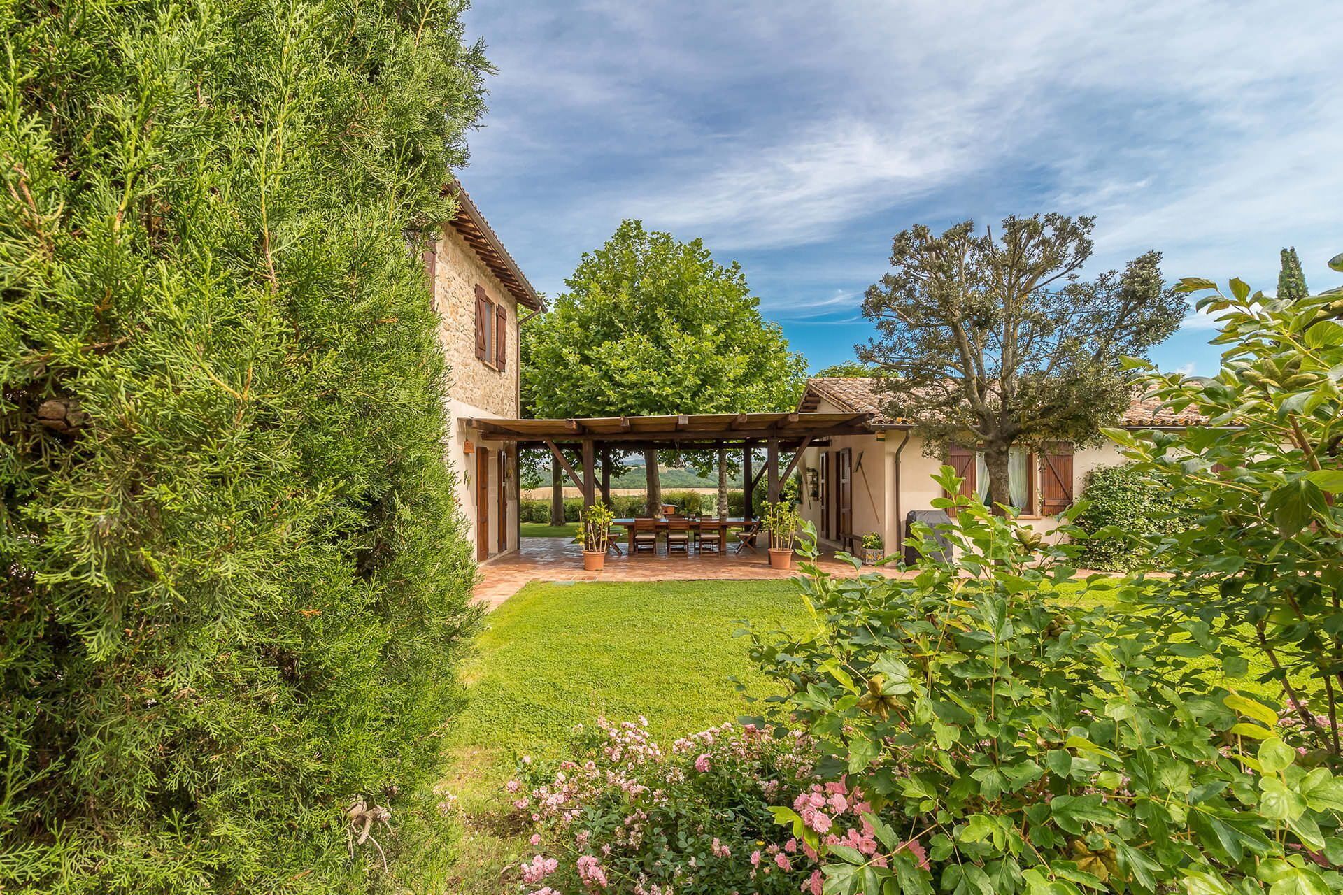 A patio area with a pergola, a table with chairs, and a view of a rural landscape.