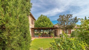 A patio area with a pergola, a table with chairs, and a view of a rural landscape.