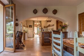 Une cuisine avec une arche en bois, une table à manger avec des chaises et un pot suspendu.