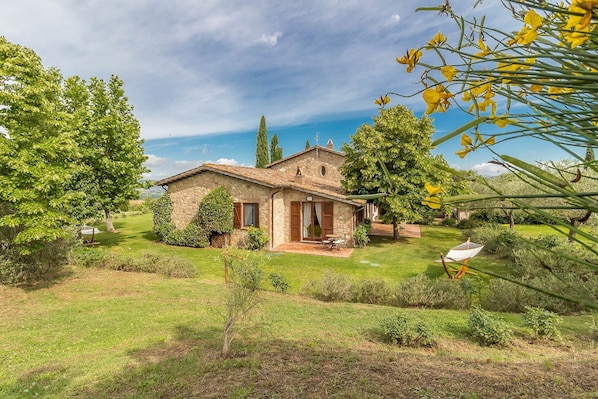 Une maison en pierre avec un jardin, une terrasse et une vue sur la campagne.