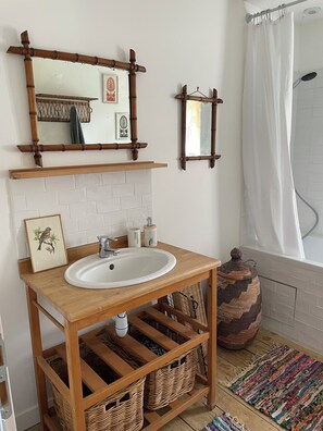 Ein Badezimmer mit einem Holzkonsolenunterschrank, einer weißen Spüle, zwei Spiegeln und einer Duschvorhang.