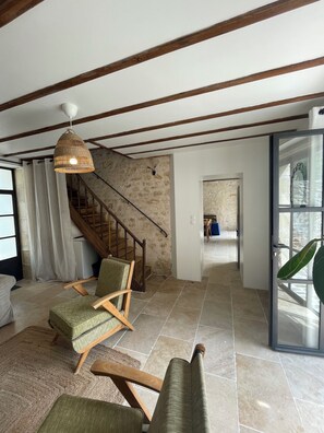 A spacious living area with a staircase, a wicker pendant light, and a view through a glass door. - Characterful Country House – Château-Fromage (Bignoux), Sleeps 4 (Bignoux)