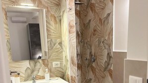 Une salle de bain équipée d’une douche, de toilettes et d’un meuble-lavabo avec un miroir.
