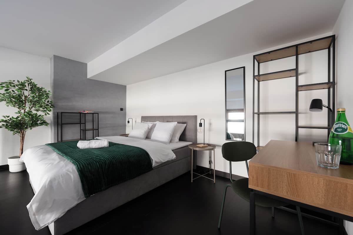 Een moderne hotelkamer met een bed, nachtkastjes, een bureau en een stoel.