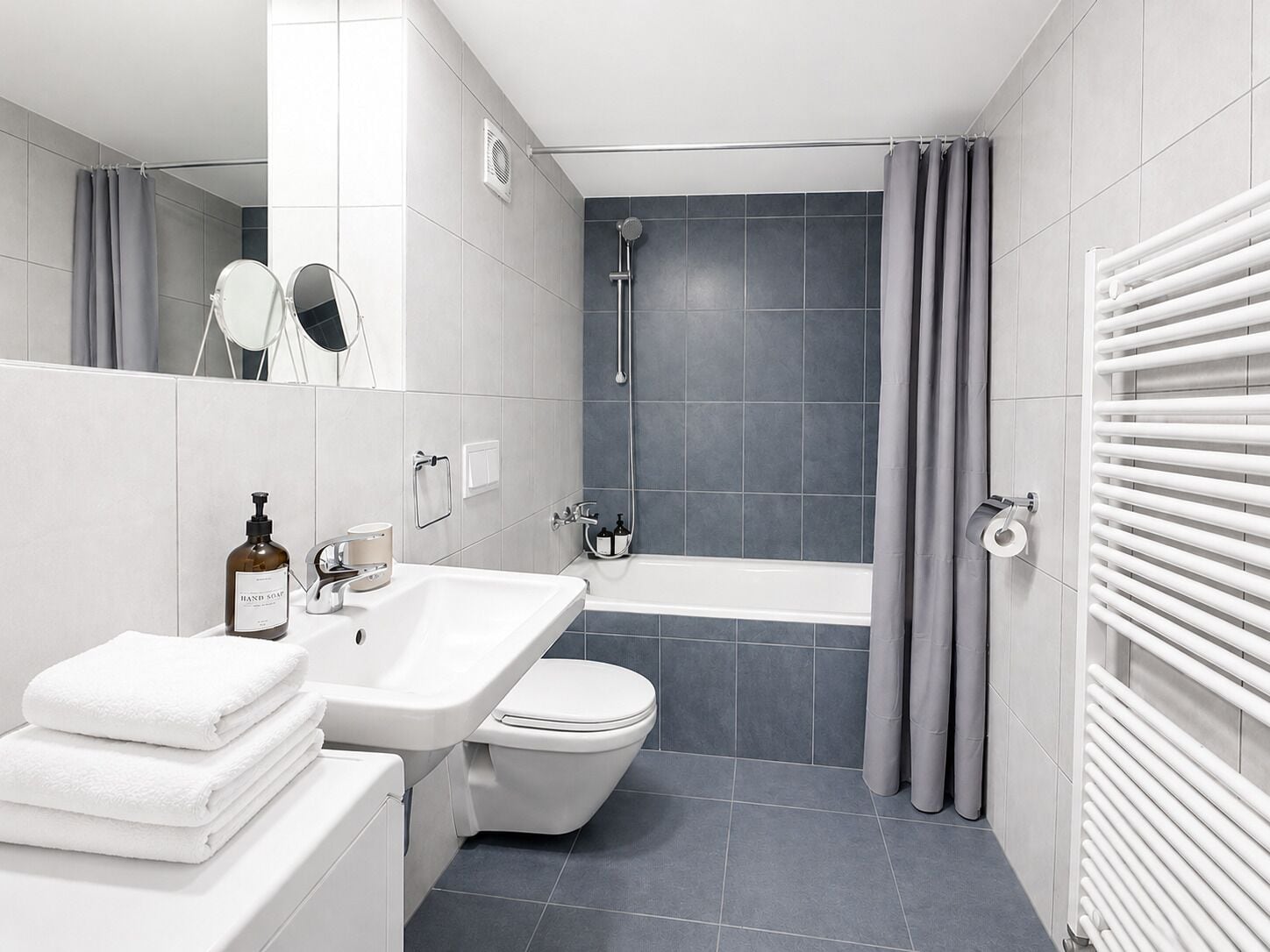 A modern bathroom with a double sink, toilet, and bathtub.