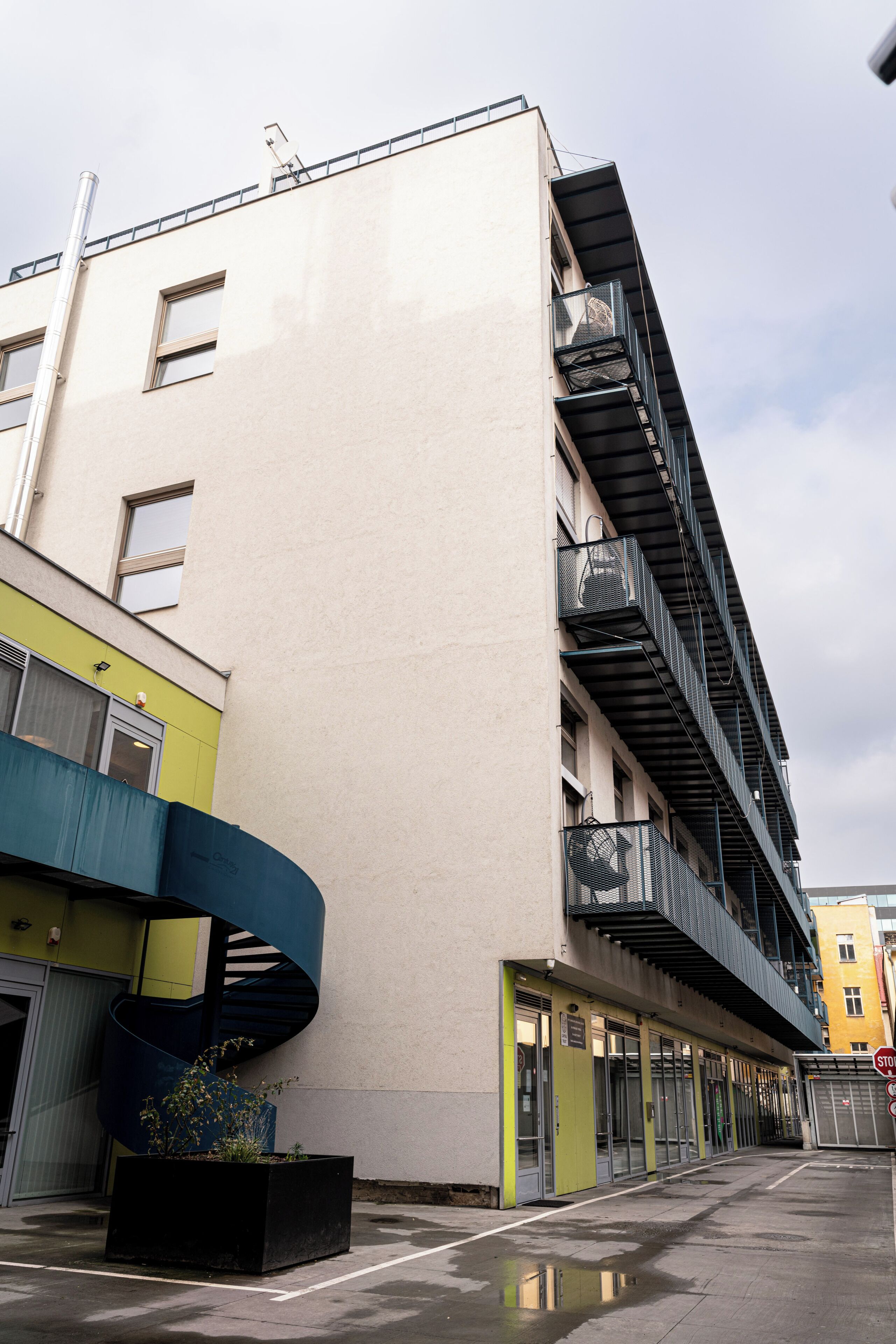 A multi-story building with a flat facade, multiple balconies, and a visible entrance with a door.