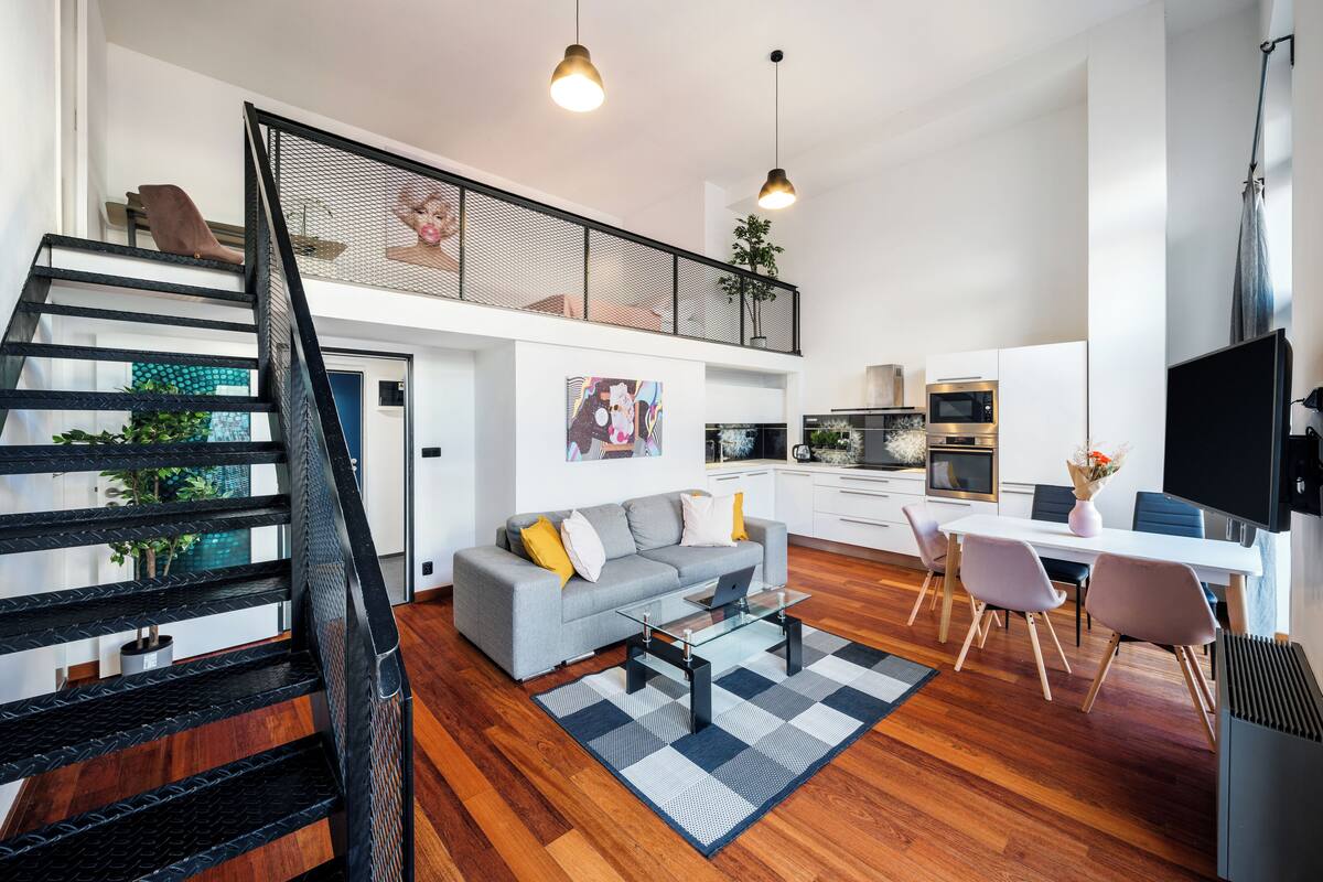 Een modern appartement met een trap, woonkamer, eethoek, keuken en een balkon.