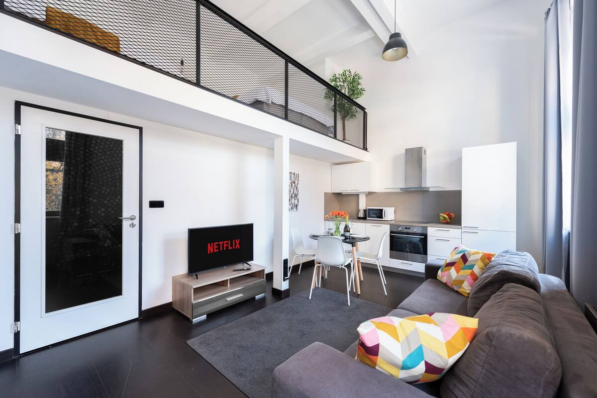Een modern appartement met een woongedeelte, kitchenette en een balkon.