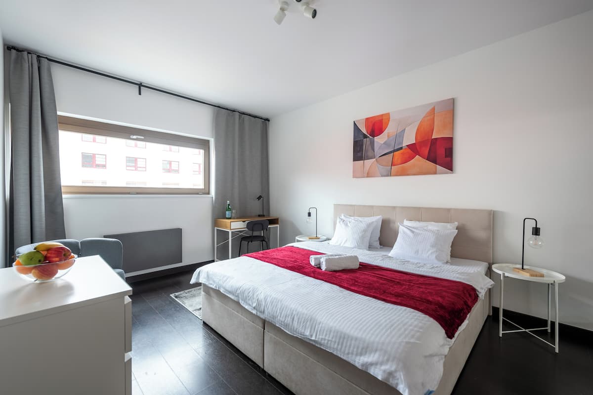 Een moderne hotelkamer met een groot bed, een bureau, een stoel en een raam met gordijnen.