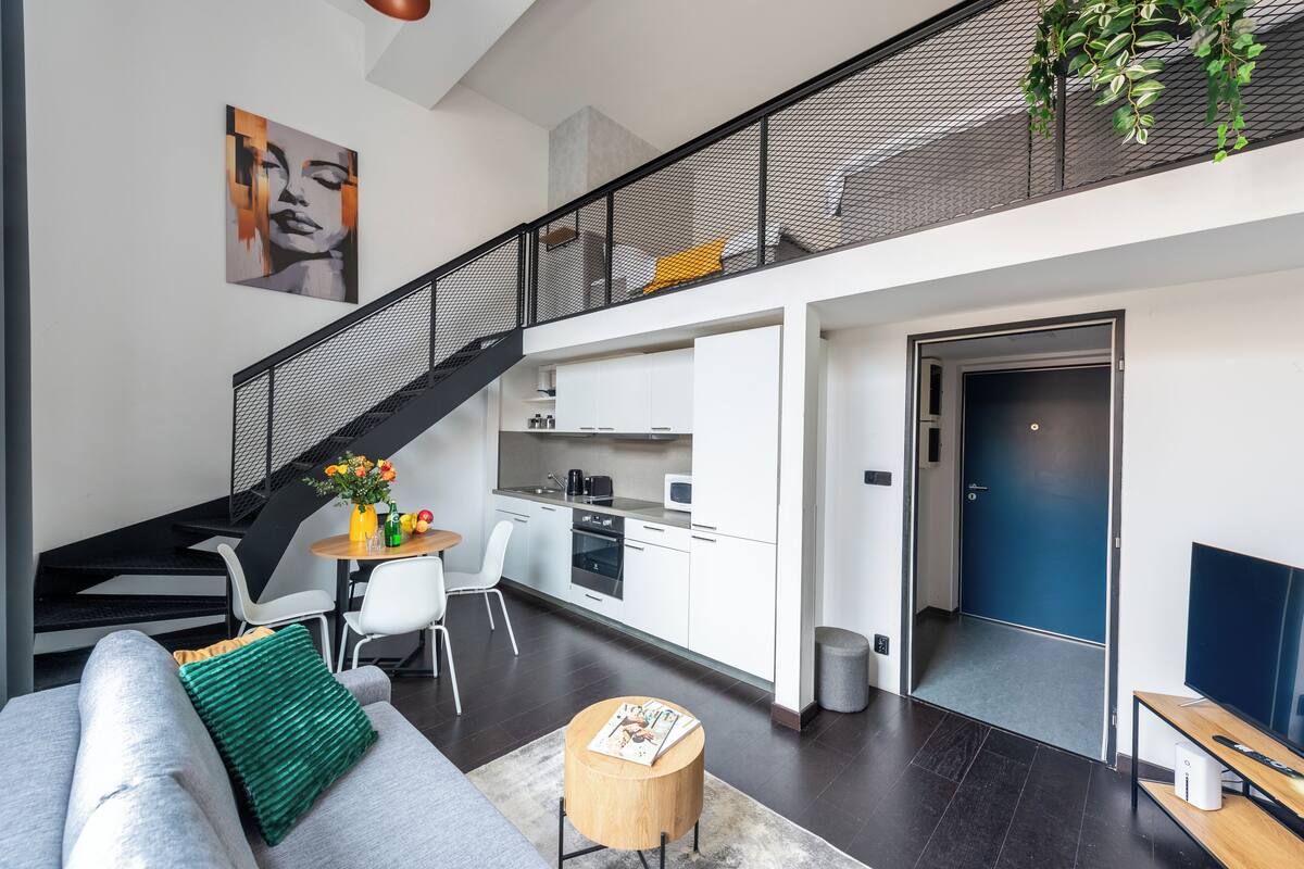Een modern appartement met een trap, keuken, eethoek en woonkamer.