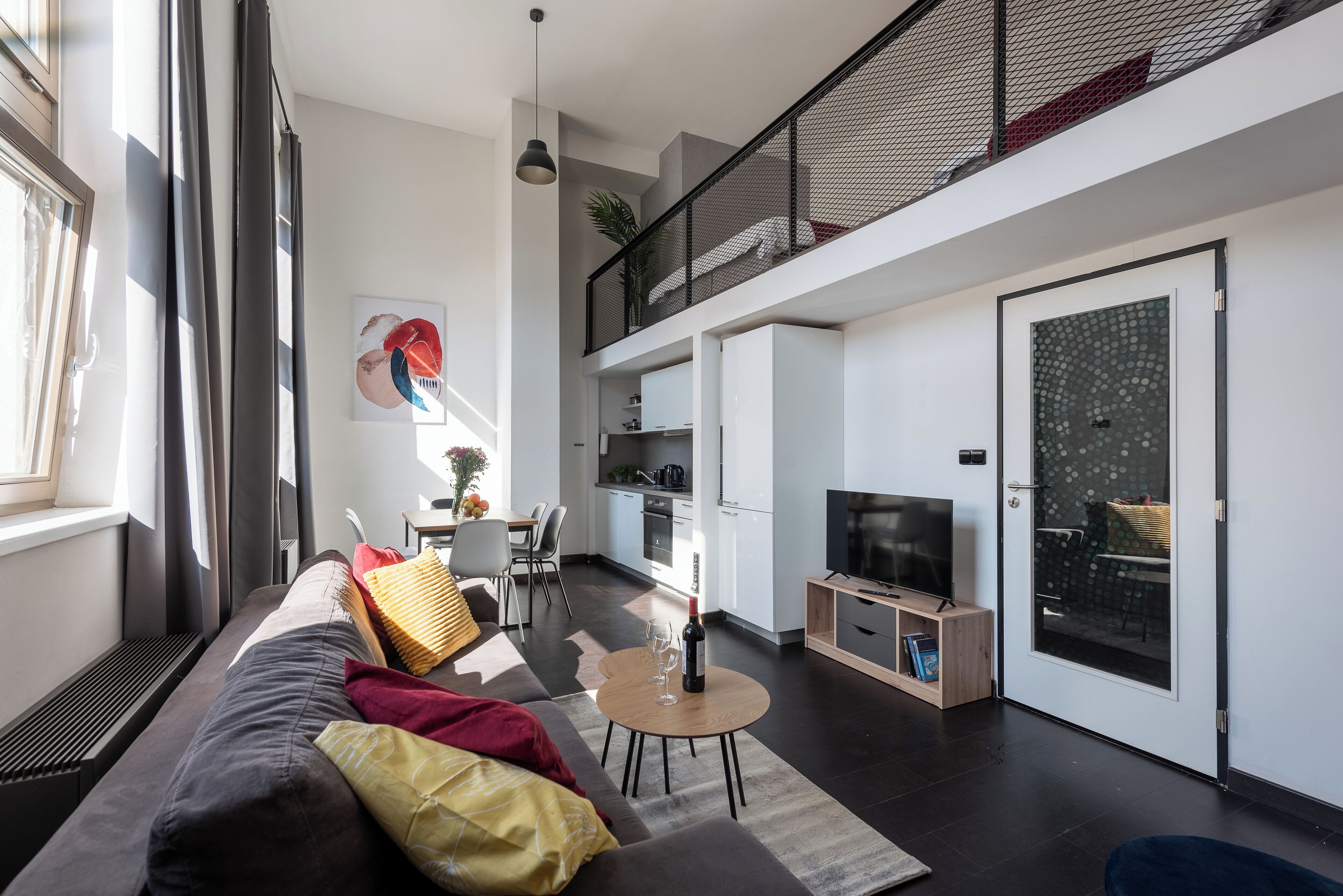 A modern apartment with a living room, dining area, kitchen, and balcony.