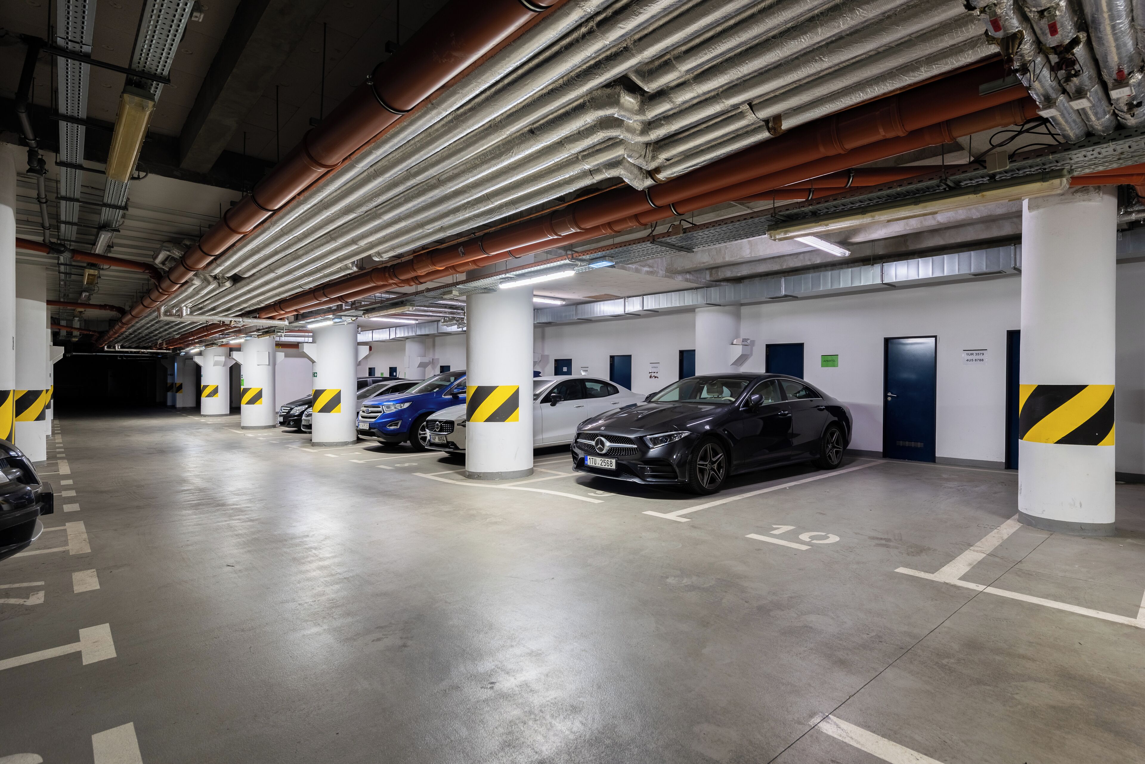 A multi-level underground parking garage with several cars parked in designated spaces.