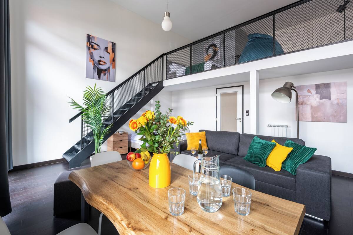 Een moderne woonkamer met een houten tafel, een bank en een trap.