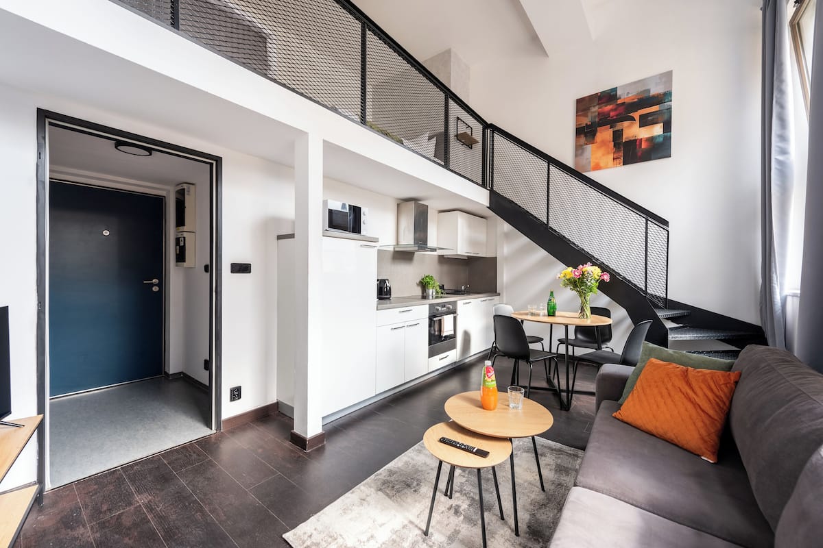 Een modern appartement met een woonkamer, eetgedeelte, keuken en een trap.