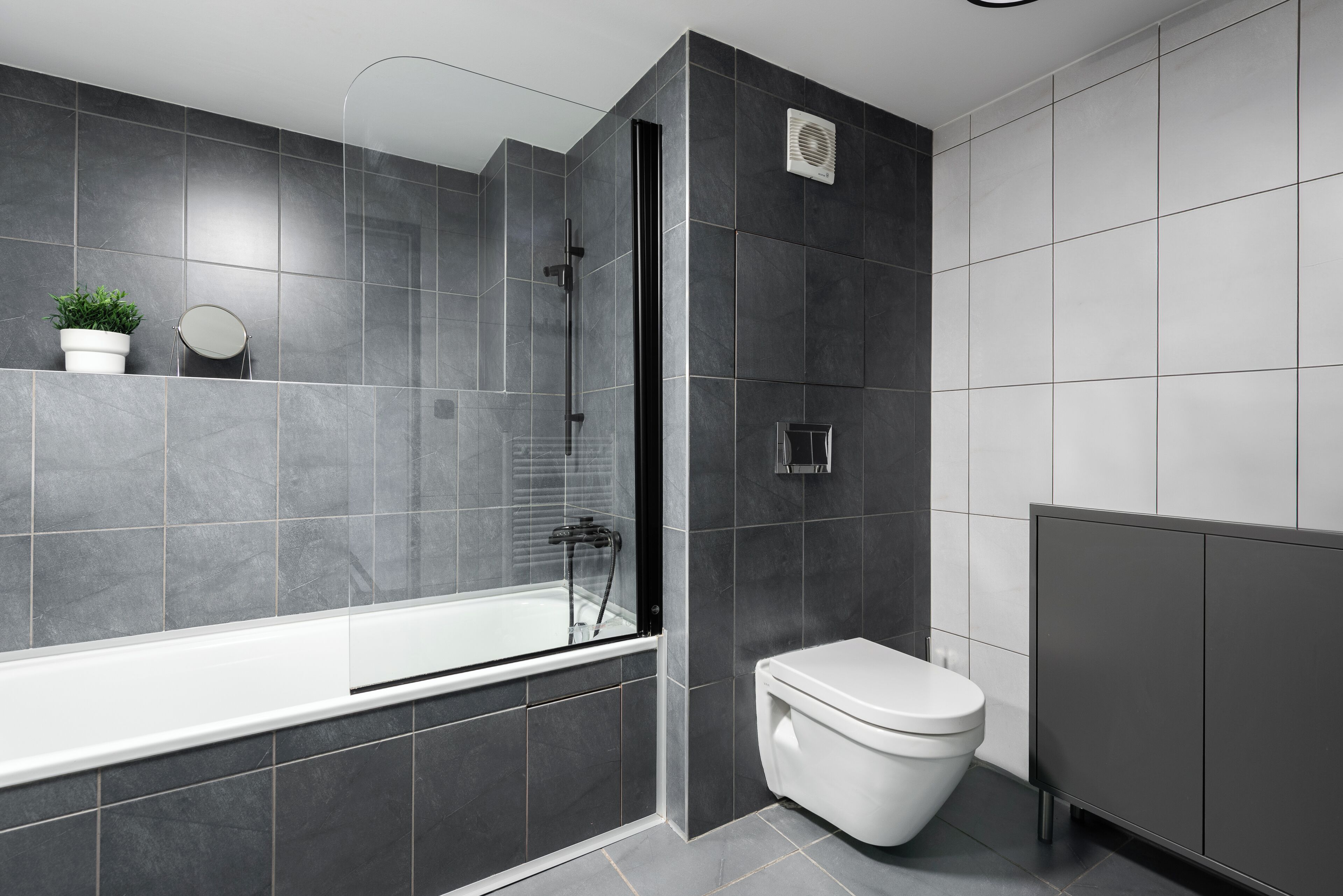 Un baño moderno con bañera, inodoro y zona de ducha.