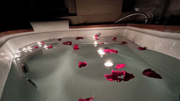 A bathtub with rose petals and candles. - Charm Apartment Rome Gemini - Relax Jacuzzi (Roma)