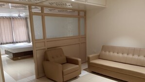 Et moderne værelse med en seng, en beige sofa og en mindre lænestol.