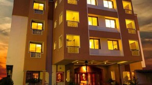 Et højt hotel med oplyste vinduer og en veloplyst indgang.