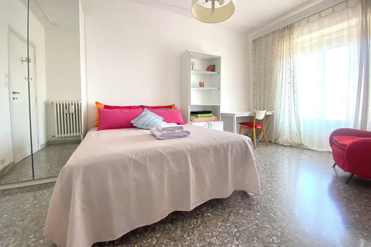 A bedroom with a bed, a desk, a chair, a wardrobe, and a radiator.