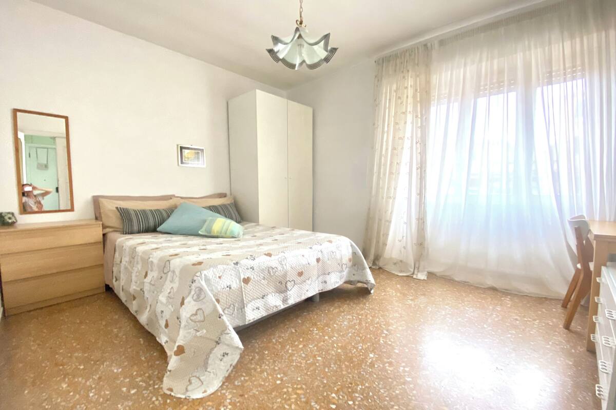 A bedroom with a bed, a wardrobe, a desk, and a chair.