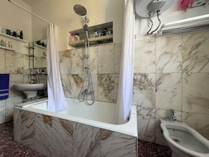 Une salle de bain avec un lavabo en marbre, une douche, un bidet et un miroir.