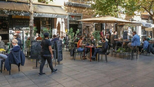 Un caffè all'aperto con tavoli e sedie, circondato da edifici.