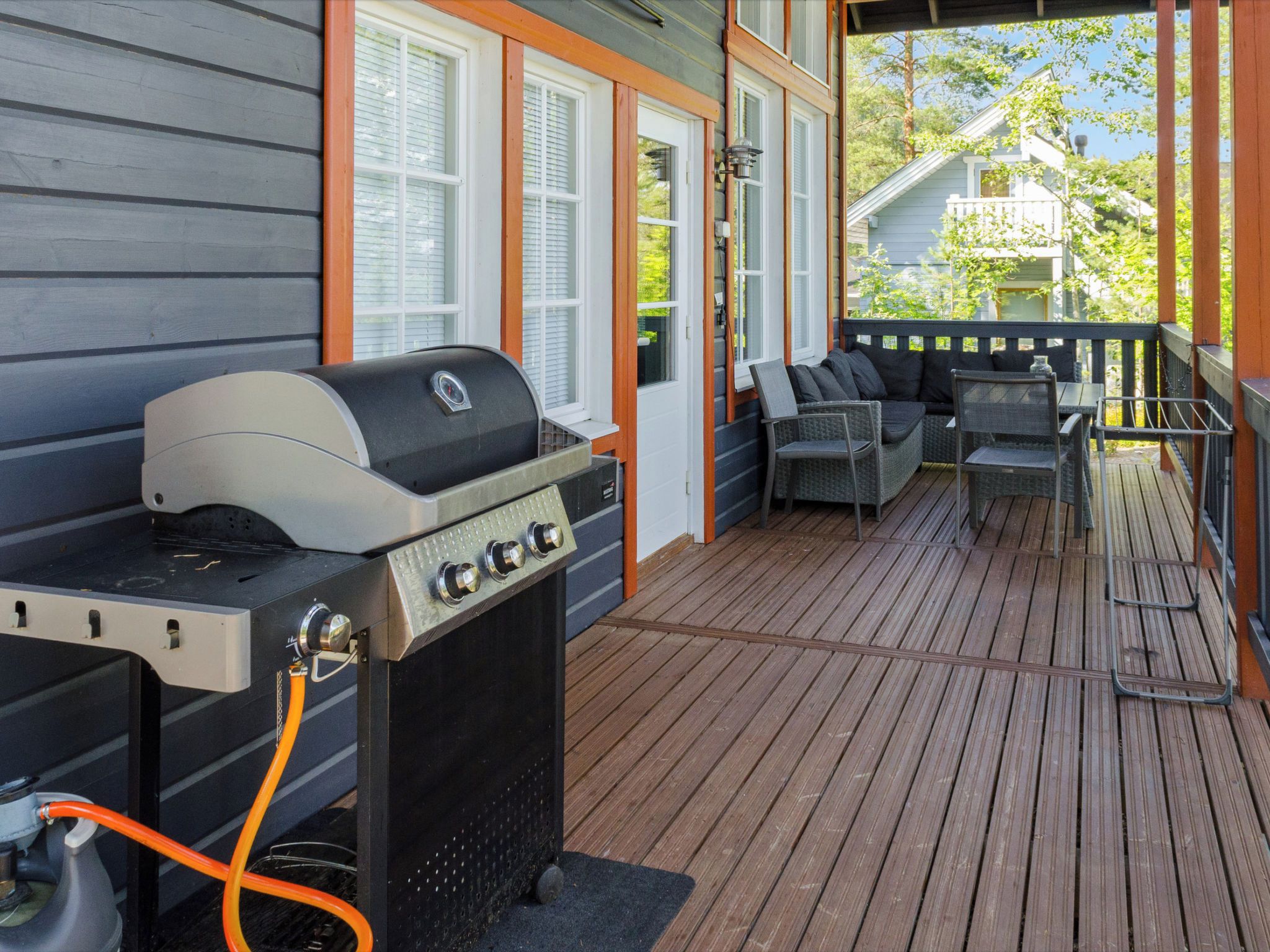 Eine Terrasse im Freien mit Grill, Sitzgelegenheit und Blick auf ein Haus.
