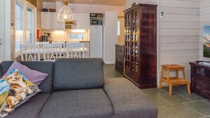 Un salon chaleureux avec un canapé gris, un meuble en bois et un petit tabouret en bois.