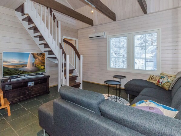 A living room with a staircase, a television, a sofa, and a window.