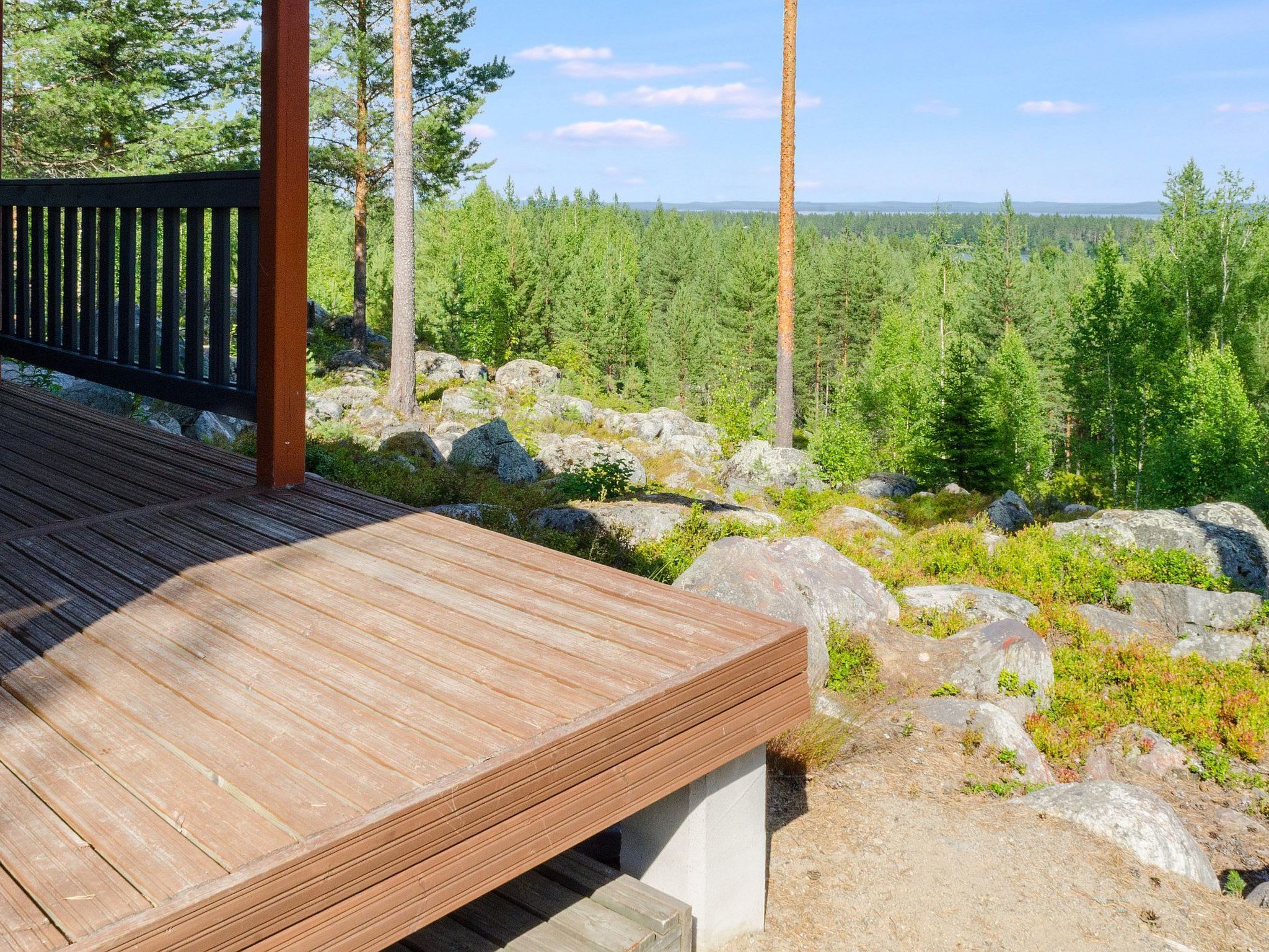 A wooden deck with a view of a forest and a distant body of water.