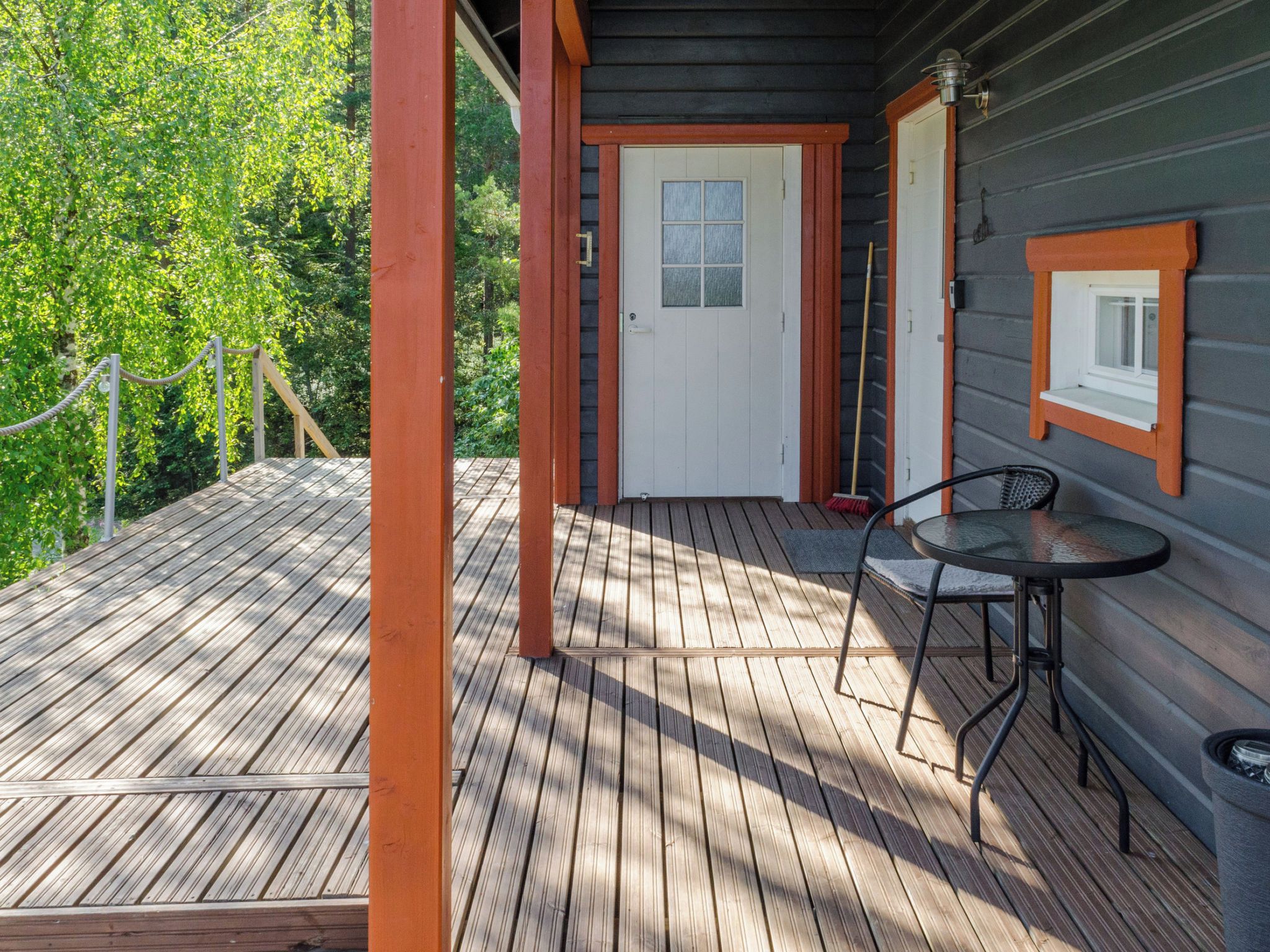 A wooden deck with a table and chairs, a door, and a window.