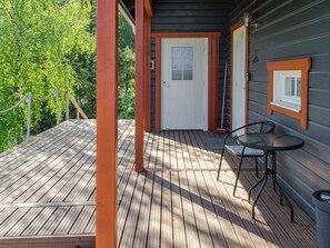 A wooden deck with a table and chairs, a door, and a window.