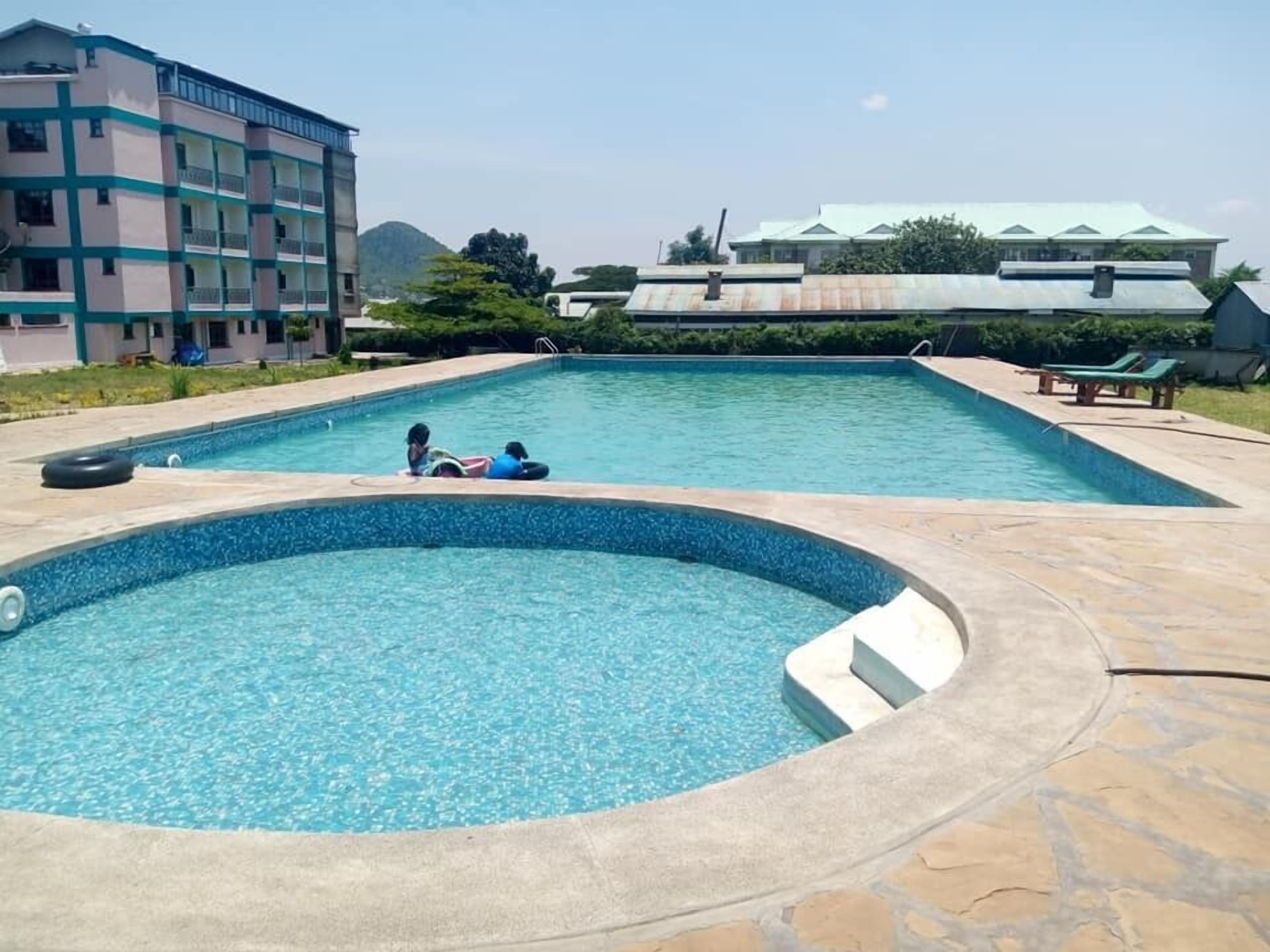 Una piscina con un pequeño espacio de hidromasaje, rodeada de baldosas de piedra.