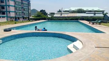 Una piscina con un pequeño espacio de hidromasaje, rodeada de baldosas de piedra.