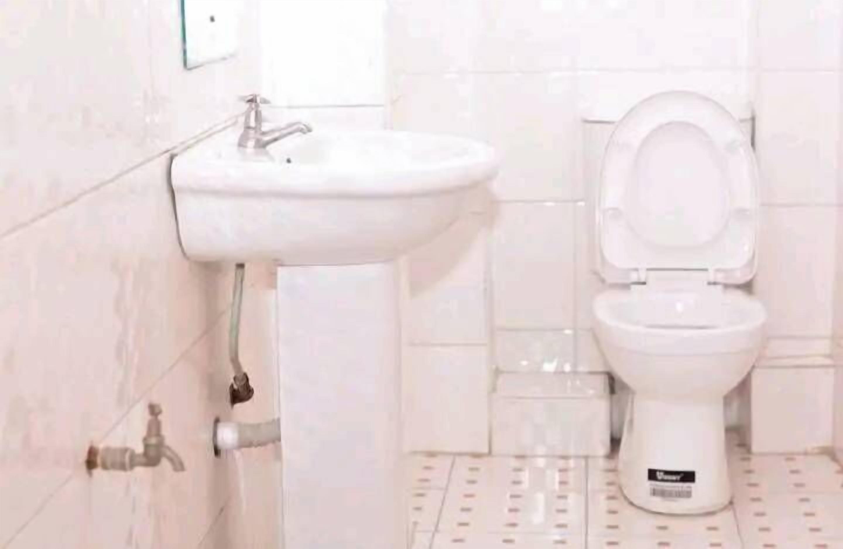 A bathroom with a white sink and toilet, tiled walls, and a patterned floor.