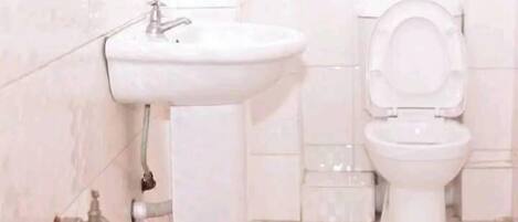 A bathroom with a white sink and toilet, tiled walls, and a patterned floor.