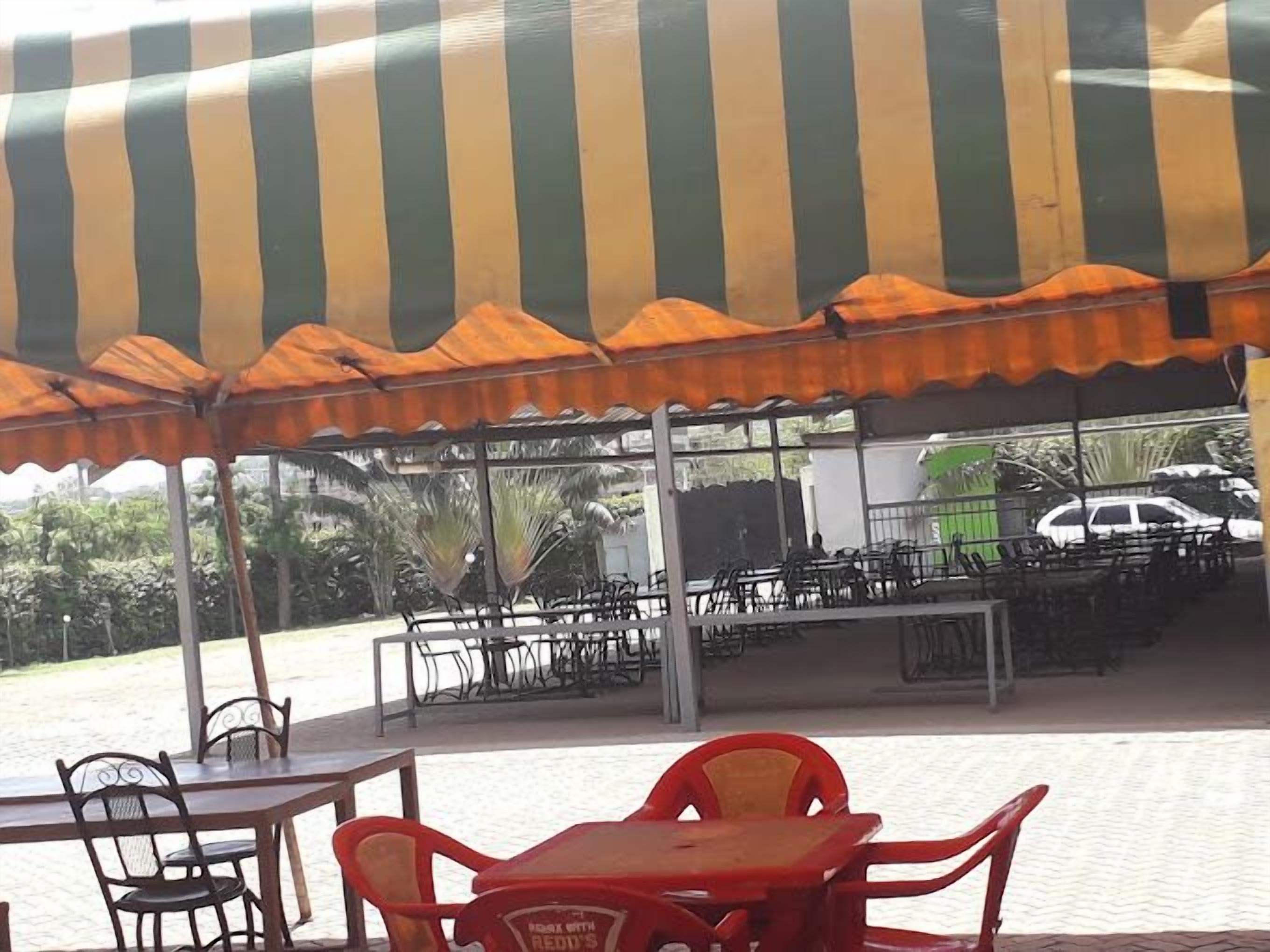 An outdoor seating area with tables and chairs under a striped awning.