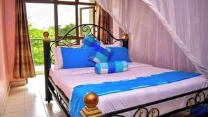 A bed with a canopy, blue bedding, and a view of greenery outside. - Hotel Staridge Limited (Homa Bay)