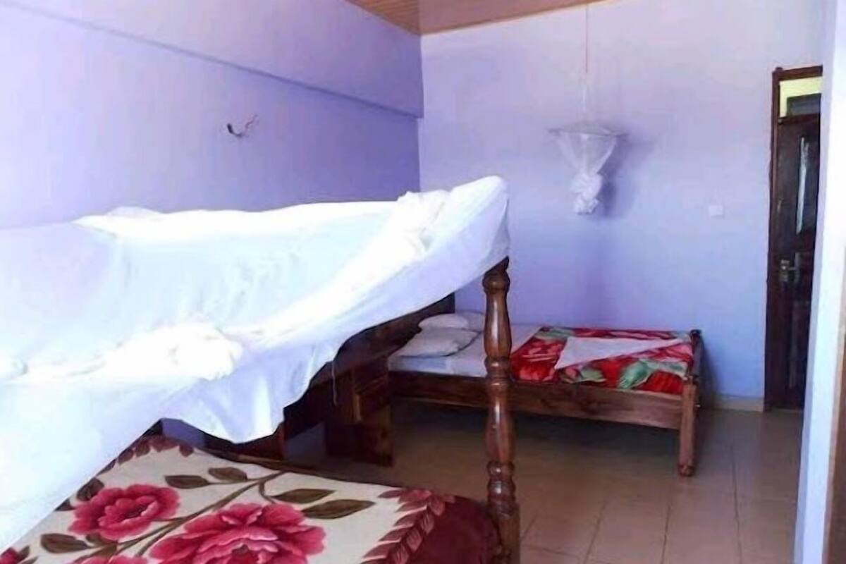 A room with two beds, one with a floral-patterned bedspread and the other with a plain white bedspread.