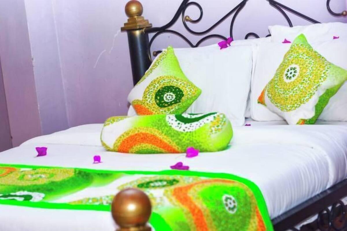 A bed with a white bedspread and decorative pillows with green and yellow patterns.