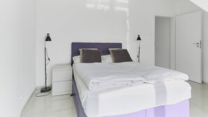A modern bedroom with a bed, bedside lamps, and a white wardrobe. - APARTAMENTY ŚWINOUJŚCIE - NOWA FLOTYLLA (Swinoujscie)