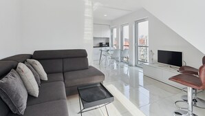 A modern living room with a grey sofa, a coffee table, and a TV on a white cabinet. - APARTAMENTY ŚWINOUJŚCIE - NOWA FLOTYLLA (Swinoujscie)