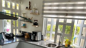 A compact kitchen with a gas stove, a sink, and a window with blinds. - Villa les Dauphins Great for Families (La Gaulette)