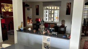 A modern kitchen with a central island, built-in shelves, and a view to the dining area. - Villa les Dauphins Great for Families (La Gaulette)