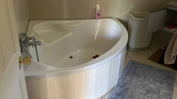 A bathroom with a freestanding bathtub, a towel rack, a trash bin, and a blue bath mat.