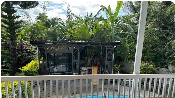 A pool area with a fenced deck, a covered seating area, and lush tropical vegetation in the background. - Villa les Dauphins Great for Families (La Gaulette)