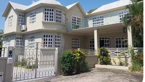 A two-story building with a flat roof, multiple windows, and a gated entrance. - Villa les Dauphins Great for Families (La Gaulette)